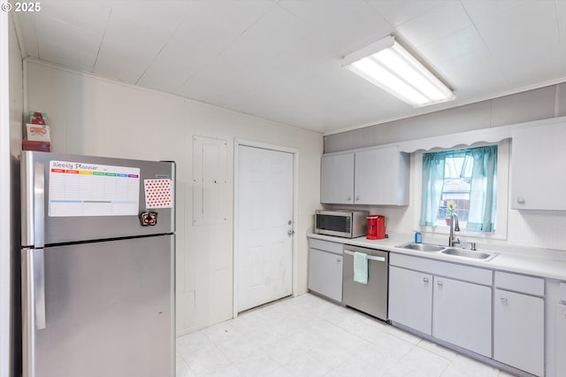 kitchen featuring light countertops, light floors, appliances with stainless steel finishes, and a sink