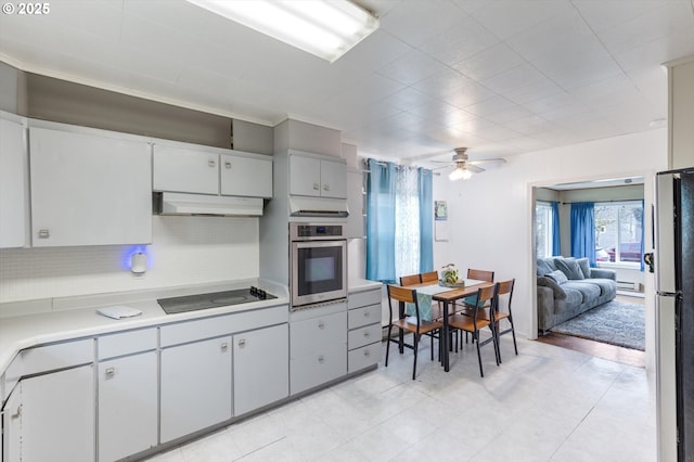 kitchen with a ceiling fan, under cabinet range hood, freestanding refrigerator, stainless steel oven, and black electric stovetop