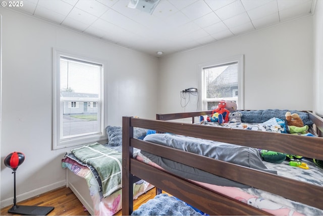 bedroom featuring multiple windows, wood finished floors, and baseboards