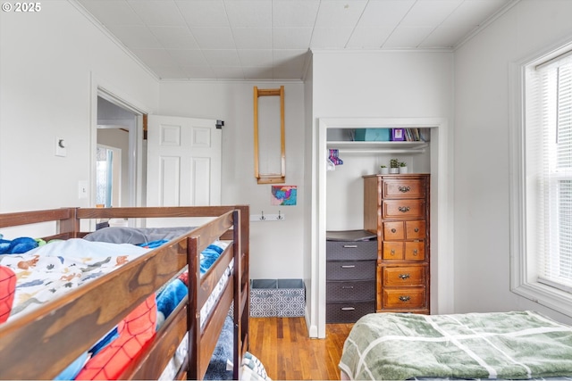 bedroom featuring wood finished floors, a closet, and ornamental molding