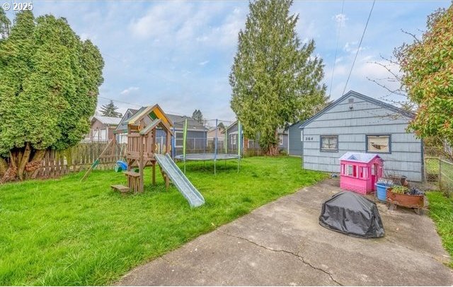 view of jungle gym with a fire pit, a trampoline, a lawn, a fenced backyard, and a patio area