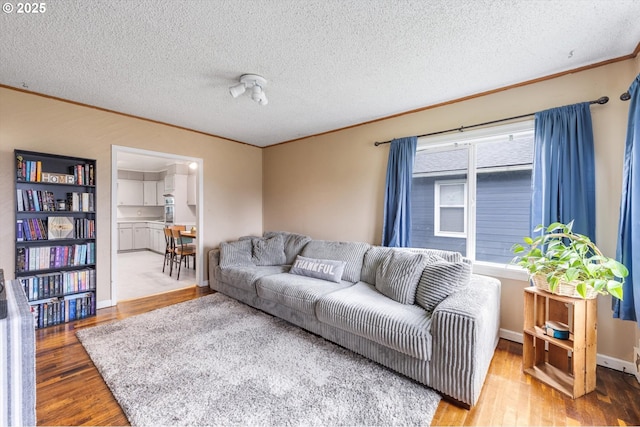 living area with crown molding, wood finished floors, and a textured ceiling