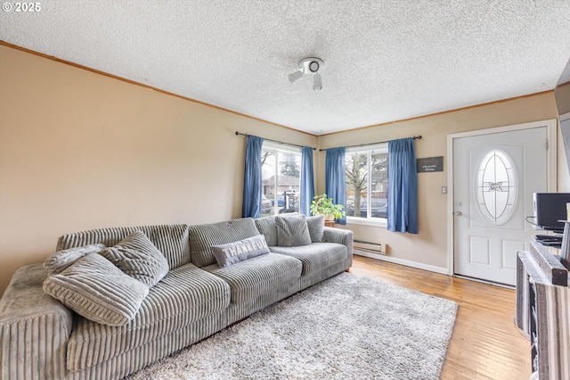 living room featuring a baseboard heating unit, a textured ceiling, wood finished floors, and ornamental molding