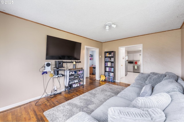 living area featuring ornamental molding, a textured ceiling, baseboards, and wood finished floors