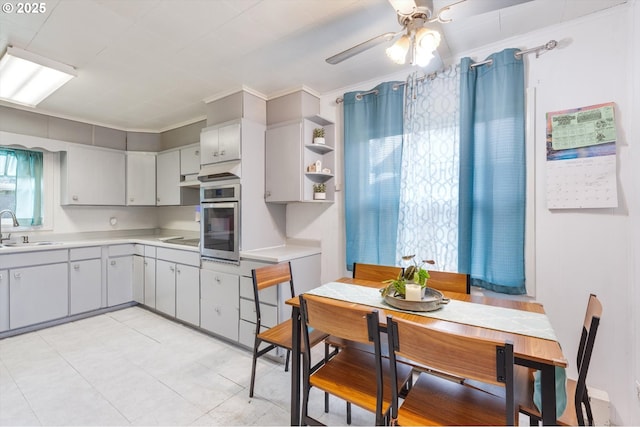 kitchen with a ceiling fan, a sink, light countertops, stainless steel oven, and black electric cooktop