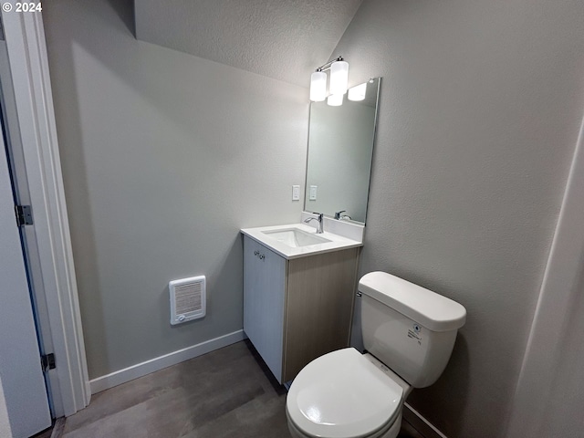 half bathroom with vanity, wood finished floors, baseboards, a textured ceiling, and toilet