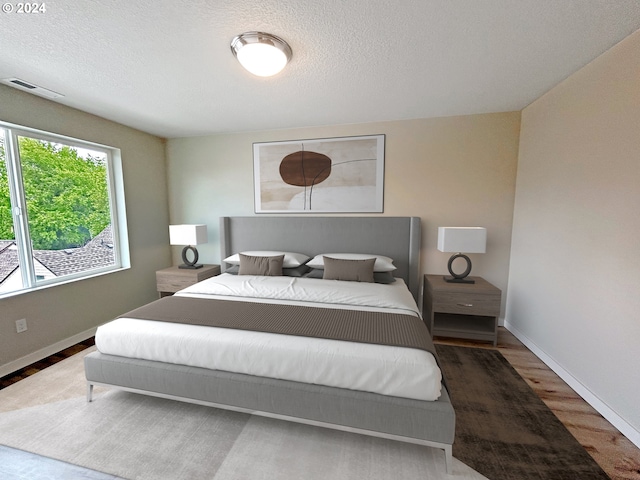 bedroom with visible vents, a textured ceiling, baseboards, and wood finished floors