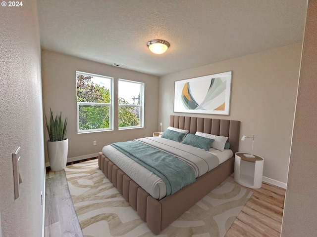 bedroom with a textured ceiling, wood finished floors, visible vents, and baseboards