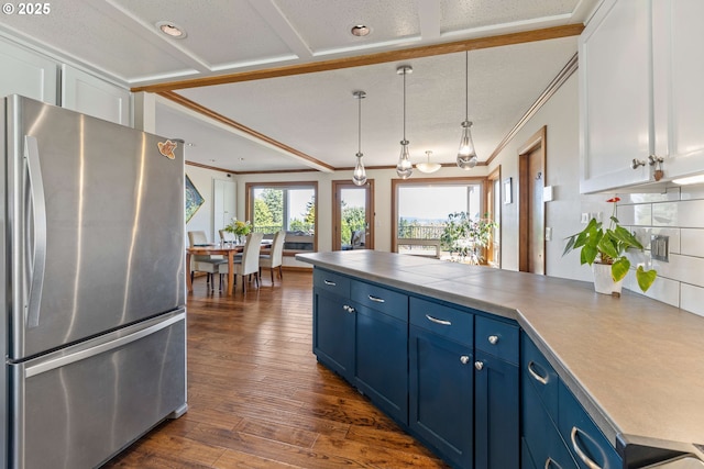 kitchen with blue cabinetry, crown molding, white cabinets, freestanding refrigerator, and a peninsula