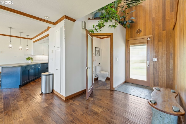 bathroom with baseboards, ornamental molding, wood-type flooring, and backsplash