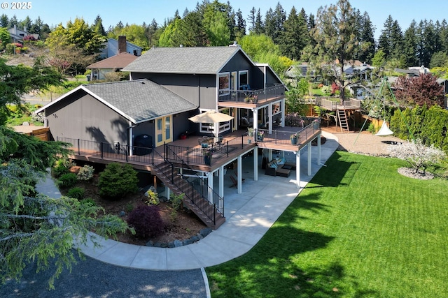 back of house with a deck, a patio, stairs, a shingled roof, and a lawn