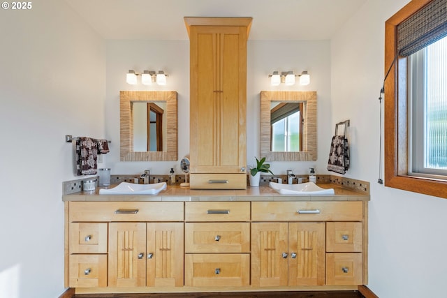 full bath with plenty of natural light, a sink, and double vanity