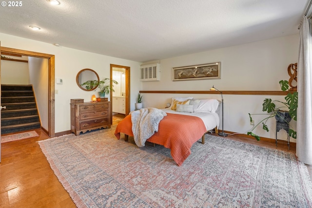 bedroom with baseboards, a textured ceiling, and wood finished floors