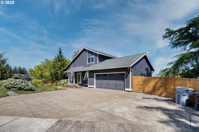 view of front of property with fence, driveway, roof with shingles, and a garage