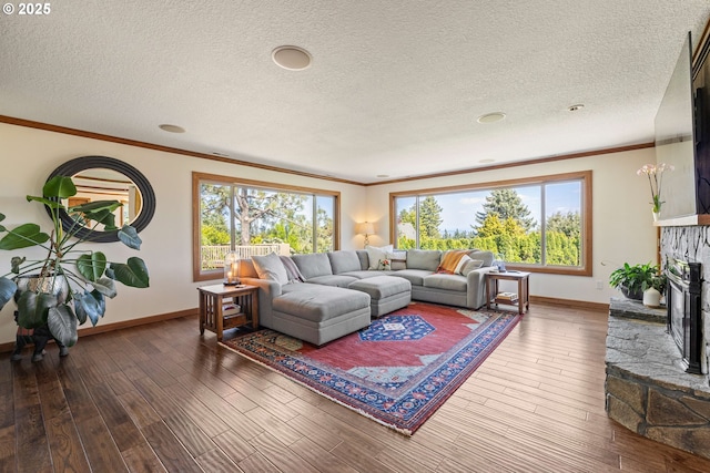 living room featuring baseboards, a fireplace with raised hearth, crown molding, and wood finished floors