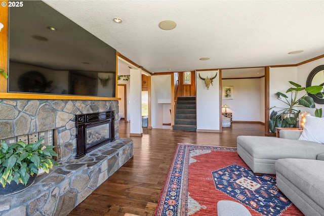 living area featuring a fireplace, wood finished floors, stairway, baseboards, and ornamental molding