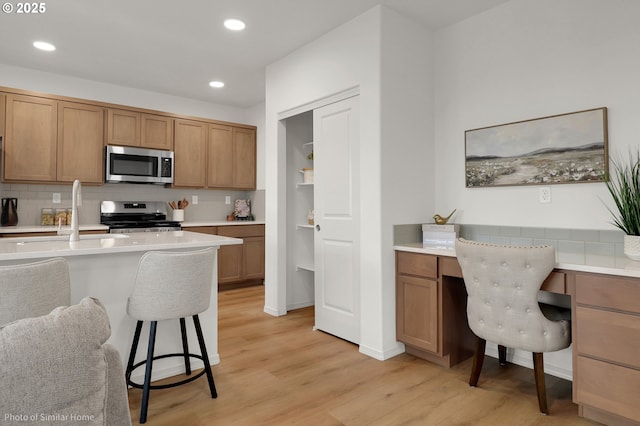 1033 Sommerville Loop, Harrisburg, OR 97446 - kitchen featuring appliances with stainless steel finishes, decorative backsplash, a breakfast bar, a sink, and light wood-style floors