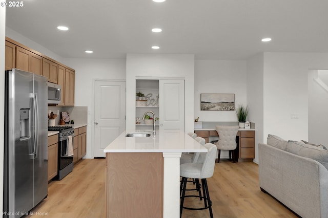 1033 Sommerville Loop, Harrisburg, OR 97446 - kitchen featuring stainless steel appliances, a sink, a breakfast bar, light wood-style floors, and light countertops