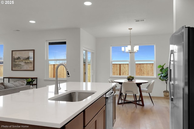 1033 Sommerville Loop, Harrisburg, OR 97446 - kitchen featuring appliances with stainless steel finishes, a sink, light wood-style flooring, a chandelier, and recessed lighting