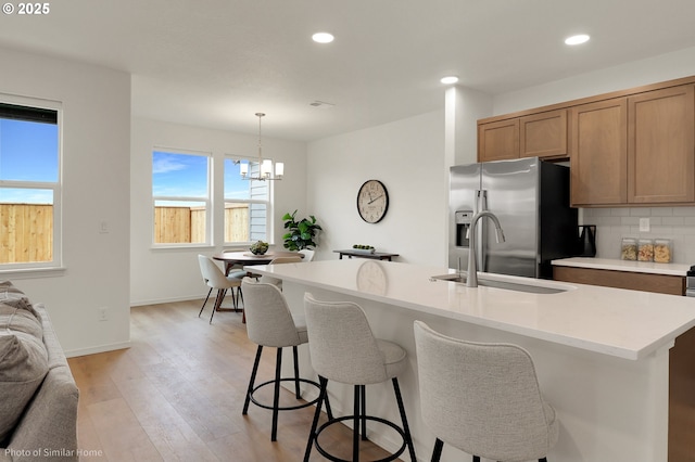 1033 Sommerville Loop, Harrisburg, OR 97446 - kitchen with stainless steel refrigerator with ice dispenser, a sink, light countertops, light wood-style flooring, and a chandelier