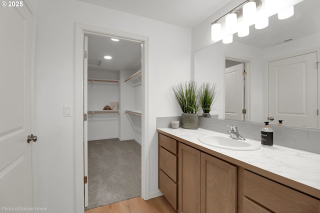 1033 Sommerville Loop, Harrisburg, OR 97446 - bathroom with vanity, a walk in closet, and wood finished floors