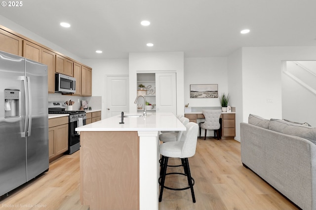 1033 Sommerville Loop, Harrisburg, OR 97446 - kitchen with appliances with stainless steel finishes, a sink, a breakfast bar area, light wood-style floors, and recessed lighting