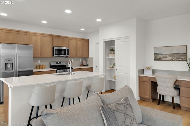 1033 Sommerville Loop, Harrisburg, OR 97446 - kitchen with stainless steel appliances, a sink, light wood-style flooring, a breakfast bar area, and open floor plan