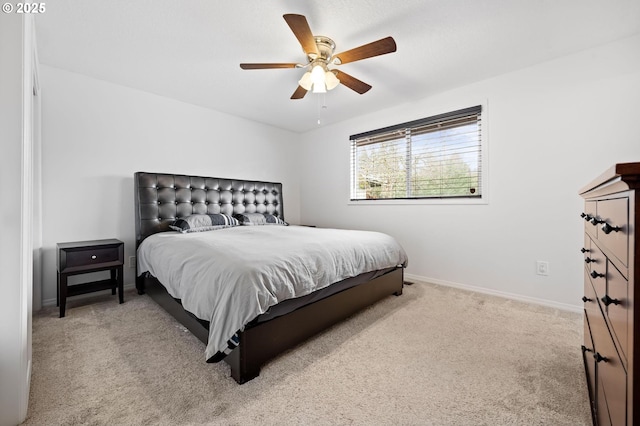 bedroom with a ceiling fan, light carpet, and baseboards