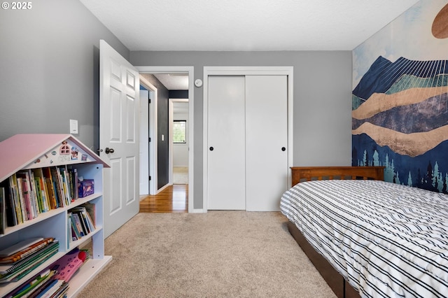 bedroom with baseboards, a closet, a textured ceiling, and light colored carpet