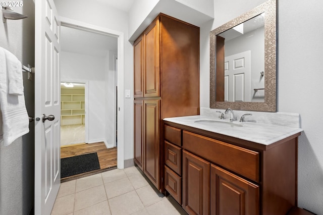 bathroom with a spacious closet, vanity, baseboards, and tile patterned floors