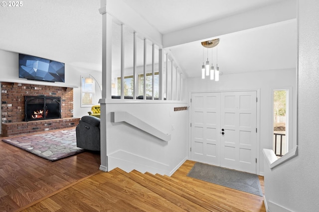 foyer featuring a fireplace, wood finished floors, and baseboards