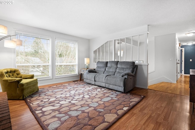 living room with a textured ceiling, baseboards, and wood finished floors