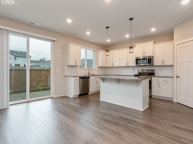6820 N 89th Loop, Camas, WA 98607 - kitchen with appliances with stainless steel finishes, white cabinets, backsplash, a breakfast bar area, and light stone counters