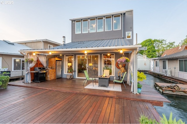 rear view of house with a fire pit, metal roof, and a wooden deck