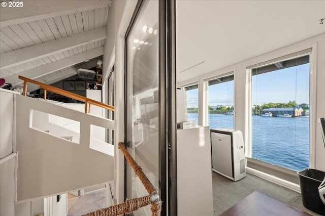 interior space with a water view, beamed ceiling, wooden ceiling, and carpet