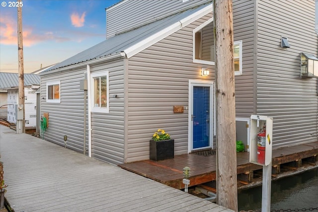 back of house at dusk featuring metal roof and a deck