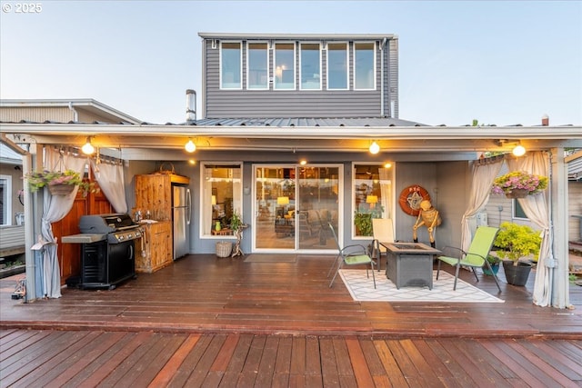 back of house with metal roof, a fire pit, and a deck