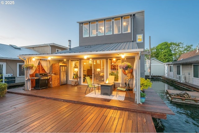 rear view of house featuring an outdoor fire pit, a wooden deck, and metal roof