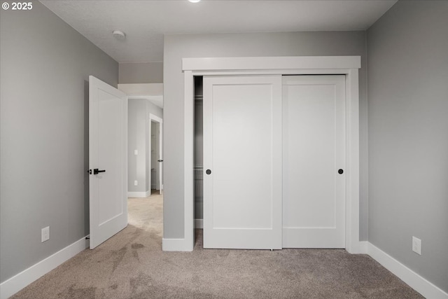 unfurnished bedroom with a closet and light colored carpet