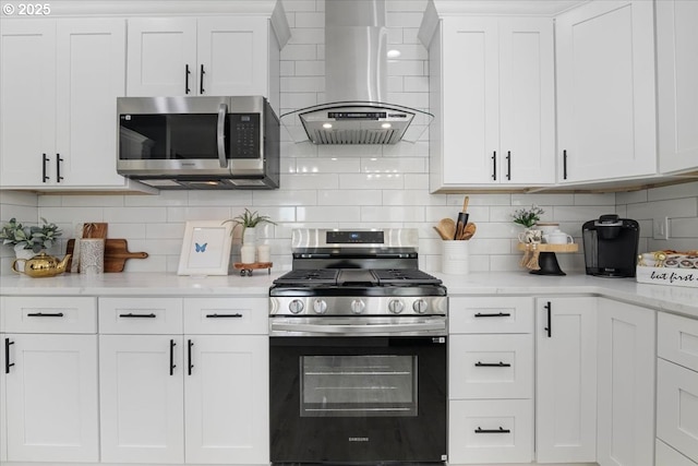 kitchen with exhaust hood, white cabinets, decorative backsplash, and appliances with stainless steel finishes