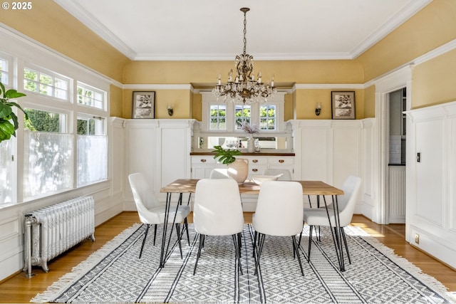 dining room featuring radiator, plenty of natural light, a chandelier, wood finished floors, and ornamental molding