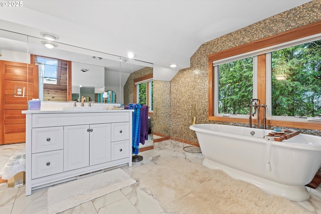 bathroom with vanity, a tub, and lofted ceiling