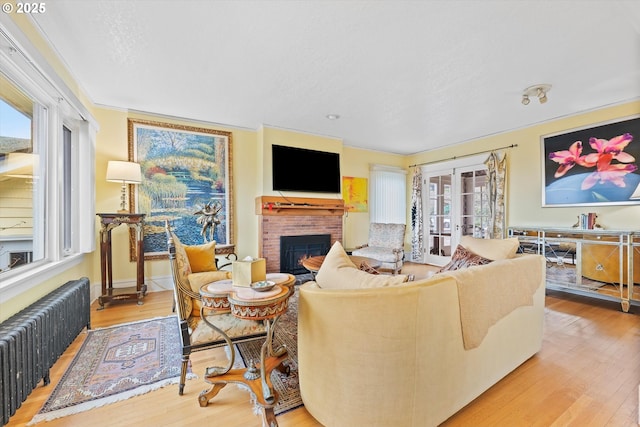 living room with french doors, radiator heating unit, a fireplace, and hardwood / wood-style flooring