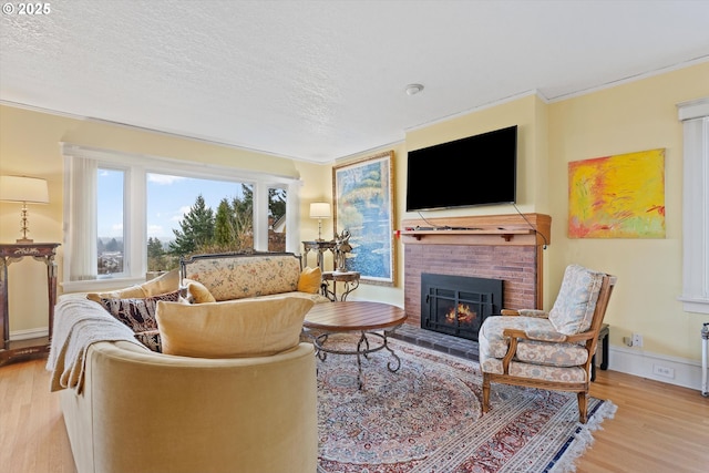 living room with crown molding, a brick fireplace, a textured ceiling, and light hardwood / wood-style floors