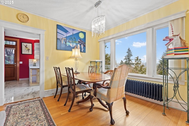 dining area featuring crown molding, radiator heating unit, a chandelier, and wood-type flooring