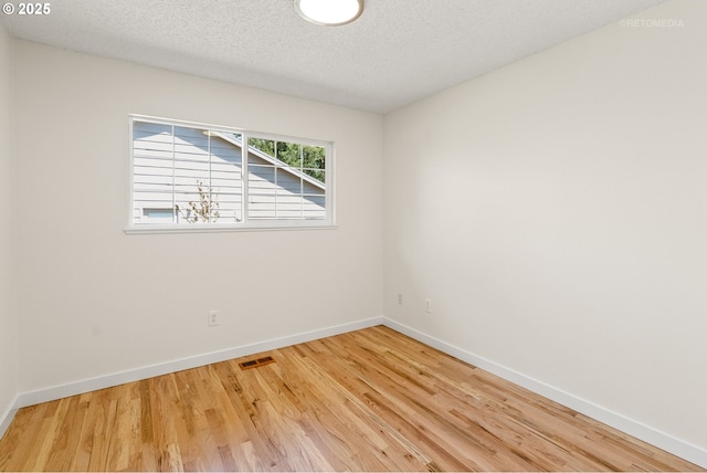 unfurnished room featuring wood finished floors, baseboards, and a textured ceiling