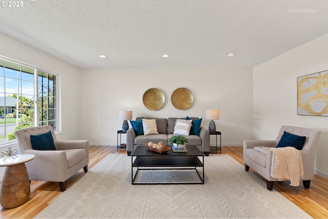 living room with light wood finished floors, recessed lighting, baseboards, and a textured ceiling
