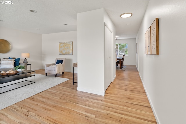 corridor featuring light wood-style floors and baseboards