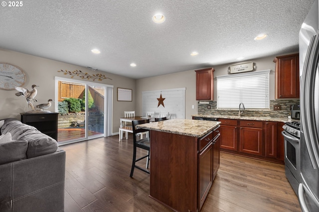 15574 Bachelor Ave, Sandy, OR 97055 - kitchen featuring appliances with stainless steel finishes, open floor plan, a breakfast bar, a textured ceiling, and plenty of natural light