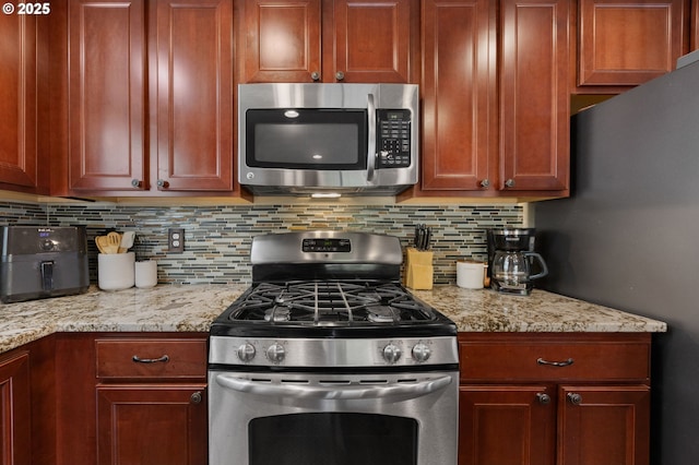 15574 Bachelor Ave, Sandy, OR 97055 - kitchen featuring appliances with stainless steel finishes, backsplash, and light stone countertops